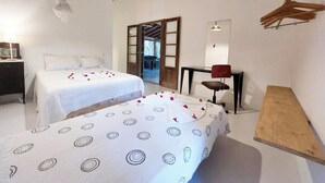 A hotel room with two beds, a bedside table, a chair, a mirror, and a wooden bench. - Mio Trancoso (Porto Seguro)