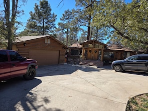 Eine zweistöckige Blockhütte mit Garage, überdachter Veranda und Auffahrt.