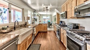 A spacious kitchen with wooden cabinets, a large island, stainless steel appliances, and a view to the dining area. - Waterfront  Hot Tub,Game room, Tahoe Keys MV25 (South Lake Tahoe)