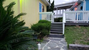 Un sendero conduce a una casa con porche blanco y puerta azul.