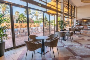A hotel lobby with a pool view, wicker chairs, and a bar area. - Agh Estepona (Estepona)