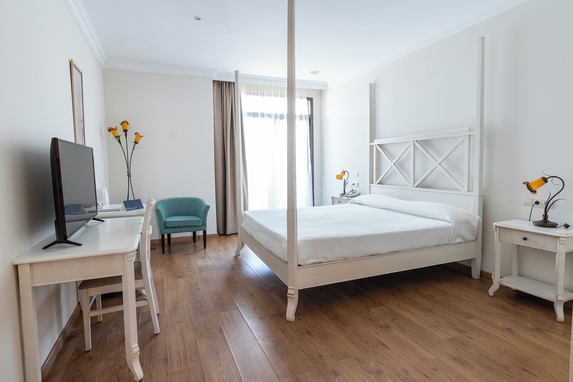 A bedroom with a bed, desk, chair, and a television.
