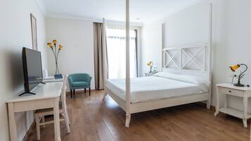 A bedroom with a bed, desk, chair, and a television.