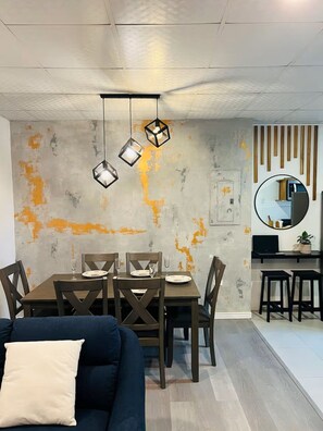 A dining area with a table set for four, a sofa, and a TV in the background.