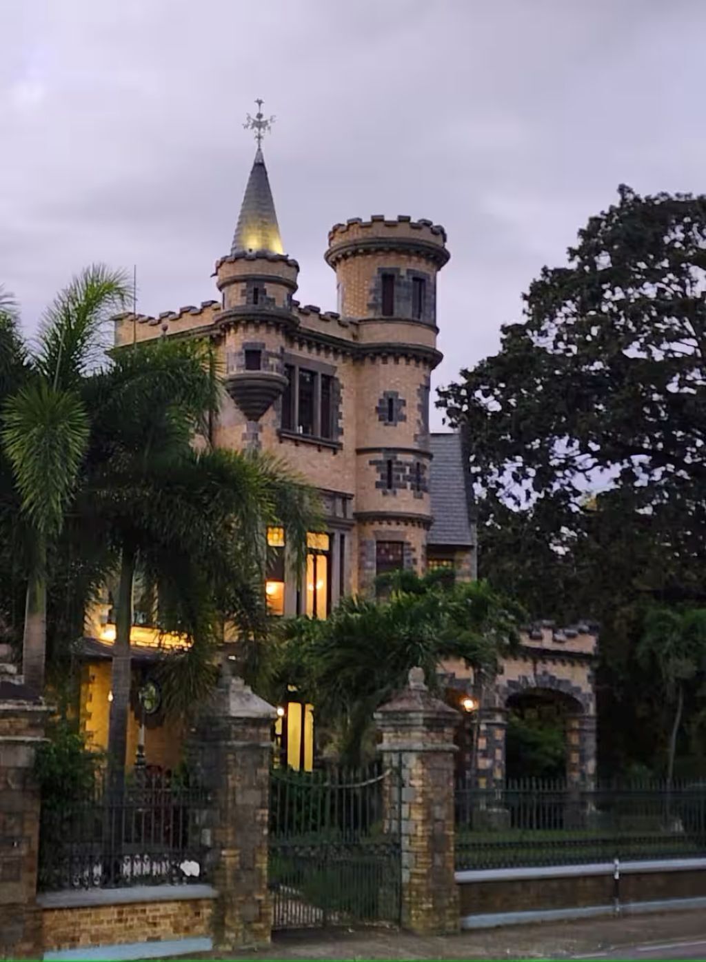Un edificio que parece un castillo, con torreones, muros de piedra y una entrada portonada.