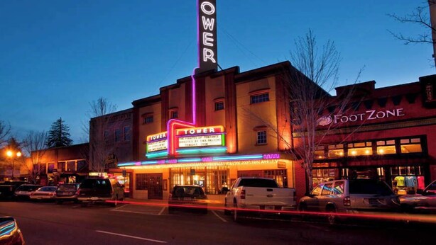Een theater met een opvallend verticaal bord, een lichtbak en een winkel genaamd 'FootZone'