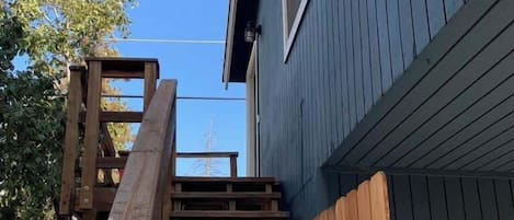 A wooden staircase leading to a house with a blue exterior.