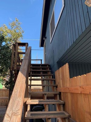 A wooden staircase leading to a house with a blue exterior. - Upper Pine Vacation Rental | Bend Living (Bend)