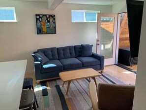 A living room with a dark blue sofa, a wooden coffee table, and a colorful striped rug. - Lower Pine Vacation Rental | Bend Living (Bend)