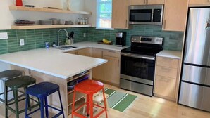 Een moderne keuken met een centraal eiland, roestvrijstalen apparatuur en een groene spatwand.