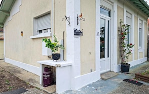 A building with a white facade, a 'Bienvenue' sign, a window with a shutter, and potted plants on the ground level. - 2 bedroom amazing home in Soulac-Sur-Mer (Soulac-Sur-Mer)