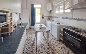 A kitchen with a tiled backsplash, a stove, a sink, and a dining area with a table and chairs. - 2 bedroom amazing home in Soulac-Sur-Mer (Soulac-Sur-Mer)