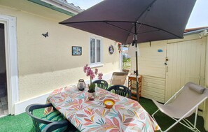A patio with a table, chairs, a large umbrella, and a potted plant. - 2 bedroom amazing home in Soulac-Sur-Mer (Soulac-Sur-Mer)