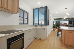 A modern kitchen with a built-in oven, a sink, and a window with blinds. - Dazzling Harbour Views, City Escape + Pool & Gym (Darwin Municipality)