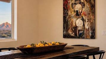 A dining area with a chandelier, a painting, and a view of mountains.