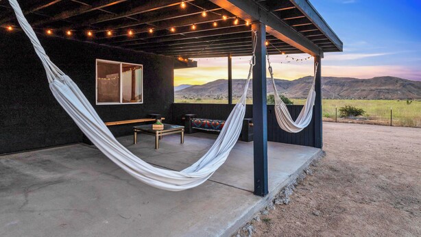 A covered outdoor area with a hammock, seating, and a view of the landscape.