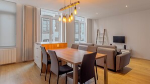 Ein modernes Wohnzimmer mit Essbereich, Sofa, Fernseher und Holzboden.