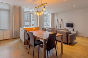 Un espacio moderno para vivir con comedor, sofá, televisor y piso de madera.