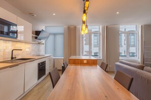 Una cocina moderna con una mesa de comedor de madera, electrodomésticos integrados y un amplio ventanal.
