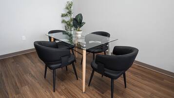 Un comedor moderno con una mesa de vidrio, sillas negras y una planta en maceta.