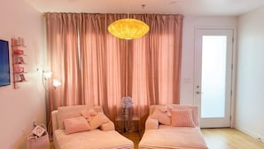 A room with two sofas, a pink rug, a hanging lamp, and a door. - Pink Longhorn + Glam Getaway + Walk to UT  Downtown Pink Longhorn (Austin)