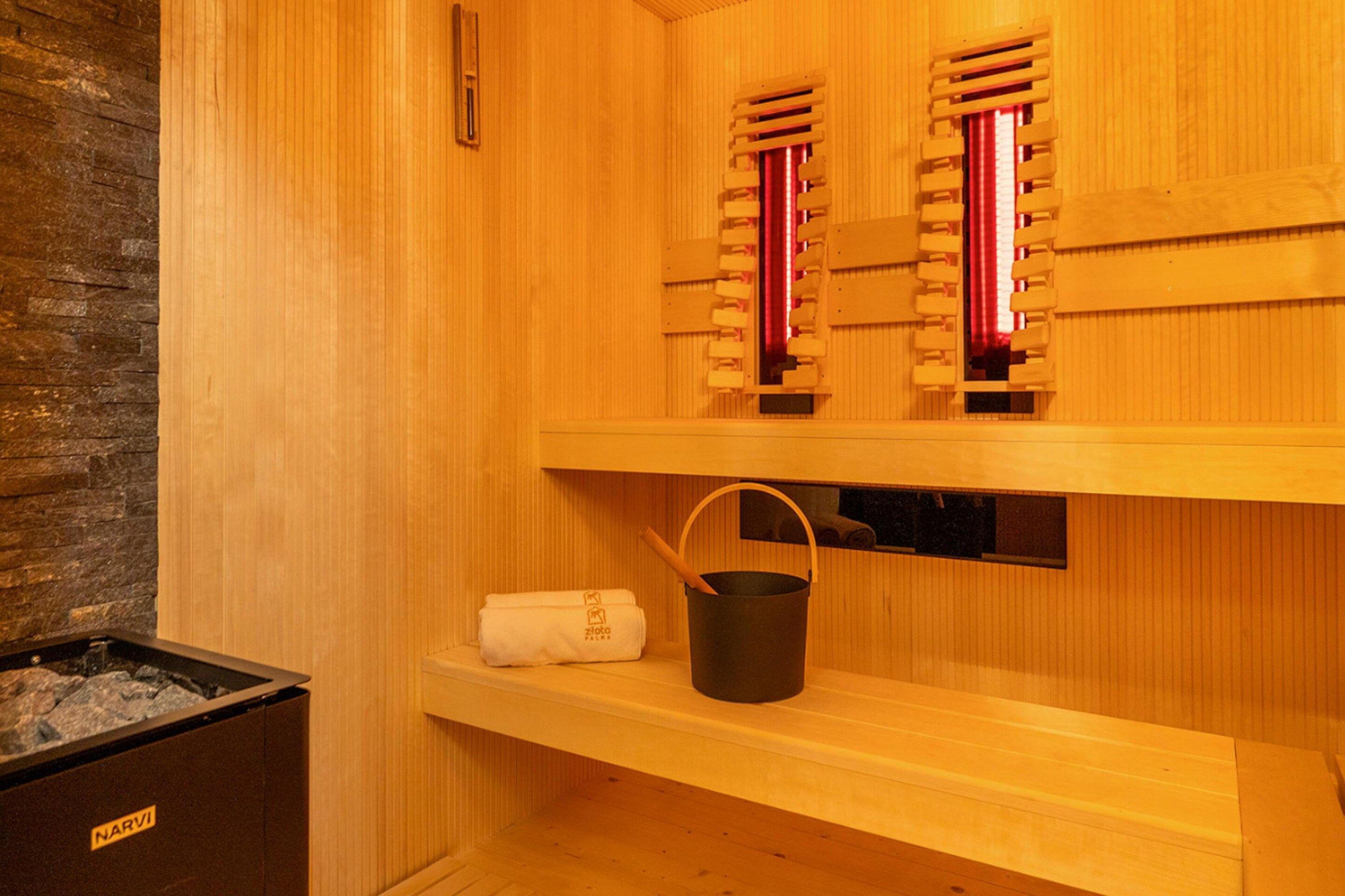 A sauna with wooden walls, a bench, a towel, and a bucket.