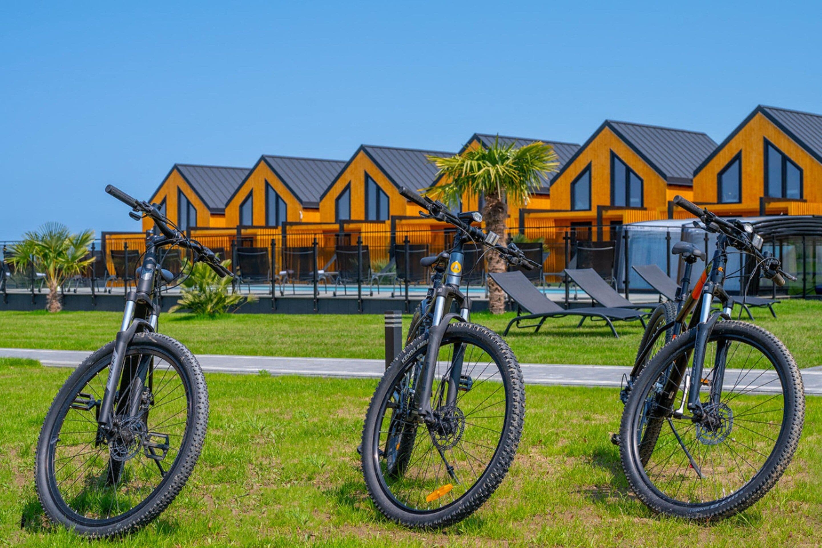 A row of mountain bikes parked in front of a modern building with a pool.