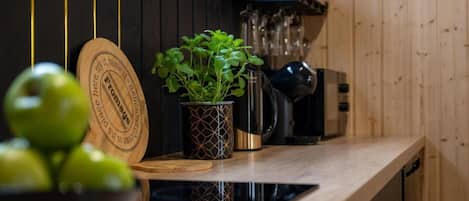 Un piano di lavoro in cucina con un tagliere di legno, una pianta in vaso, una macchina da caffè e un frullatore.