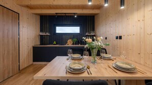 Un comedor de madera con una mesa dispuesta para cuatro, una pared de acento oscura y una ventana sobre la encimera.