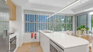 Una cocina moderna con una isla central, electrodomésticos integrados y grandes ventanales que dan a zonas verdes.