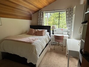 Una camera da letto con un letto, una scrivania, una sedia e una finestra con tende.