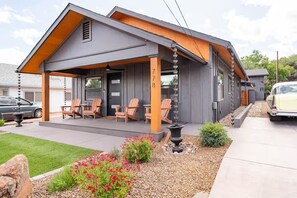 Een modern huis met een overdekte veranda, buitenmeubels en een decoratieve waterpartij.