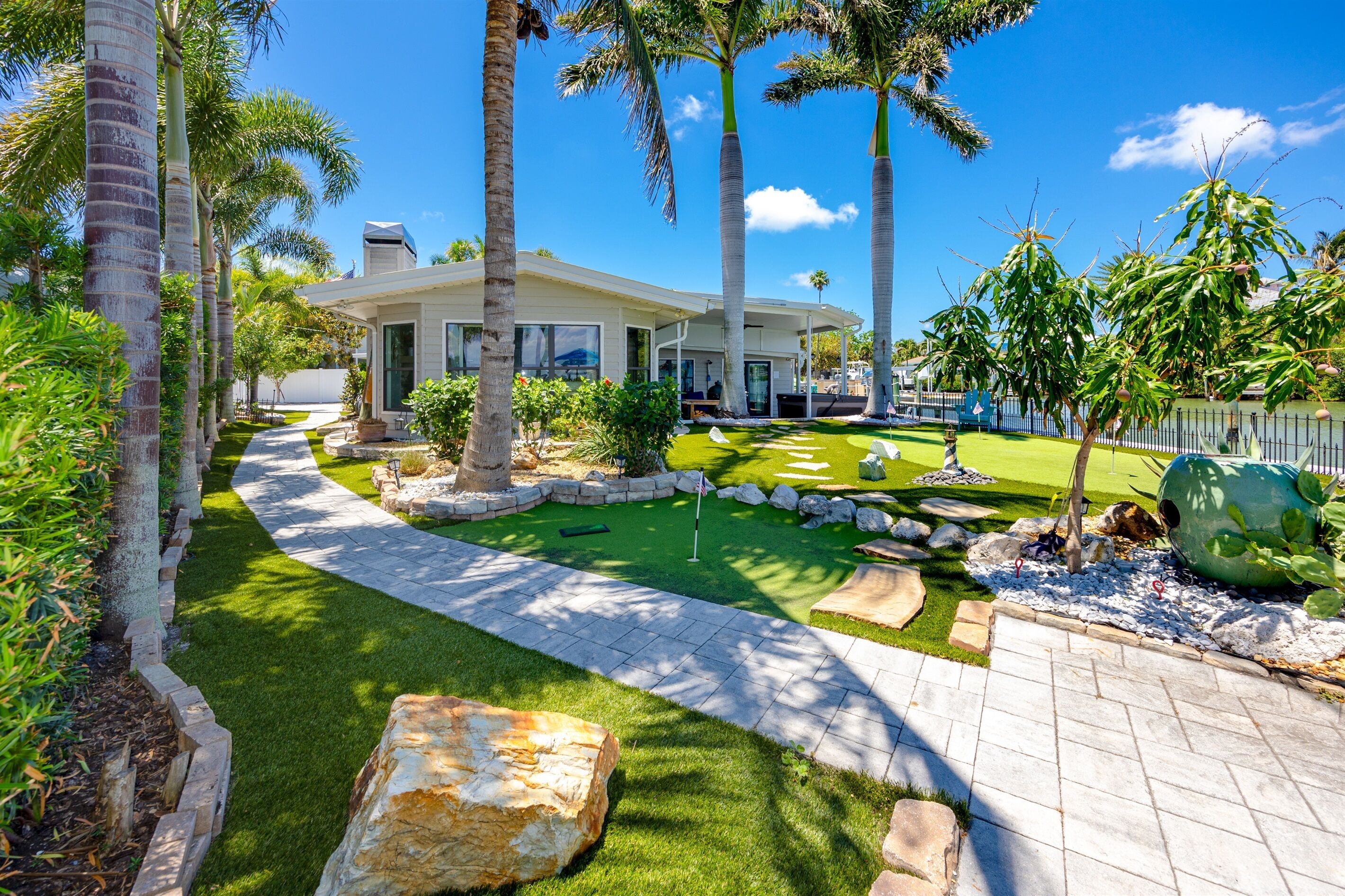 A modern house with a well-maintained lawn, a pathway leading to the entrance, and a large rock feature.