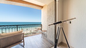 Ein Balkon mit Teleskop, Stuhl und Blick auf den Strand.