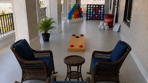 Un espacio al aire libre techado con mobiliario de mimbre, una mesita y un juego de mesa de madera.