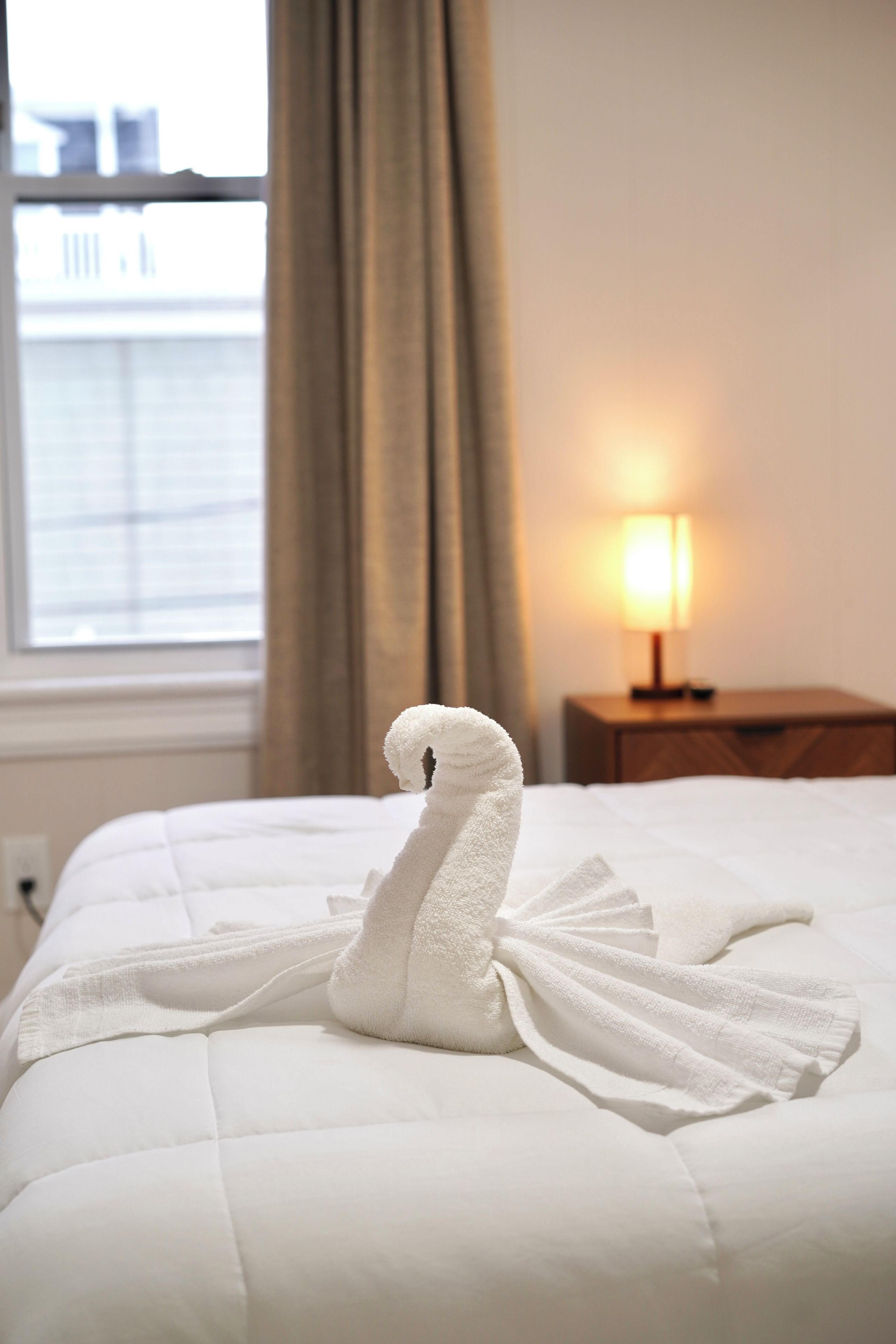 A bed with a towel arranged in the shape of a swan.