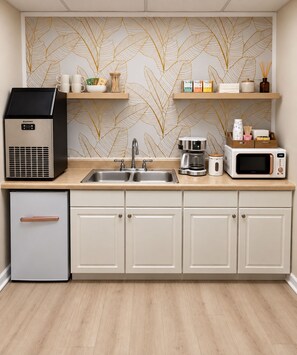 Una cocina con extractor de humos empotrado, un lavamanos doble, cafetera y microondas.