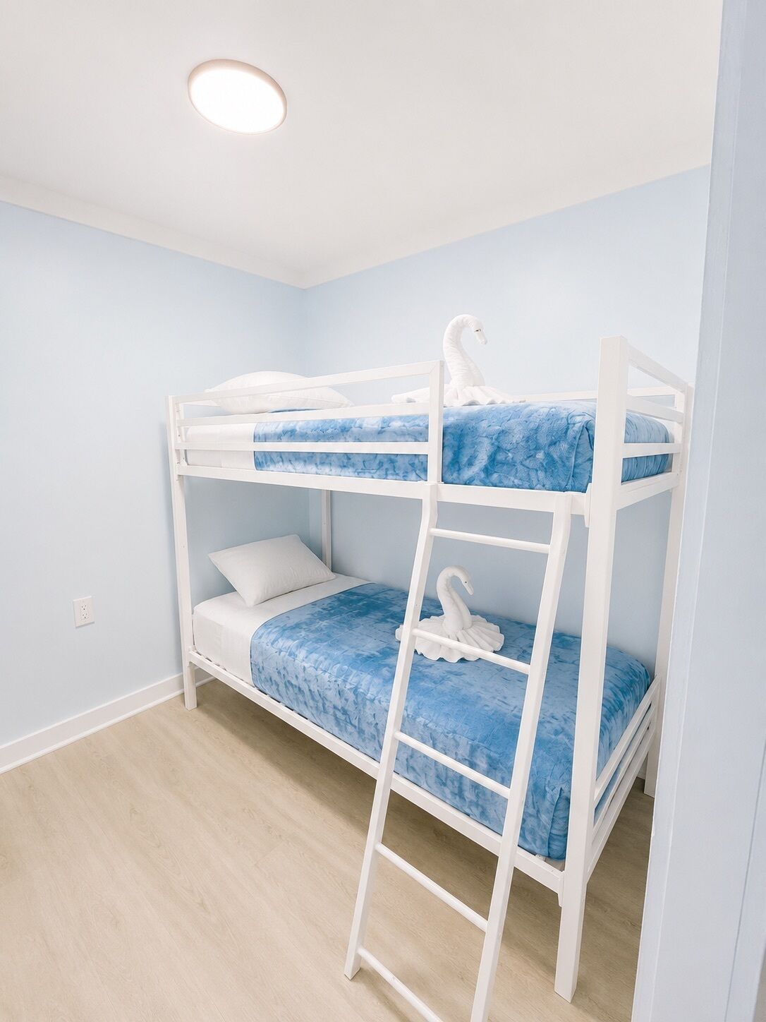 A bunk bed room with a ladder, white railings, and a swan decoration on the lower bunk.