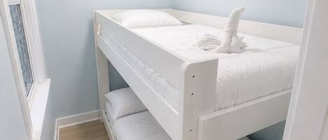 Camera con letto a castello, una finestra, pareti azzurro chiaro e pavimento in legno.