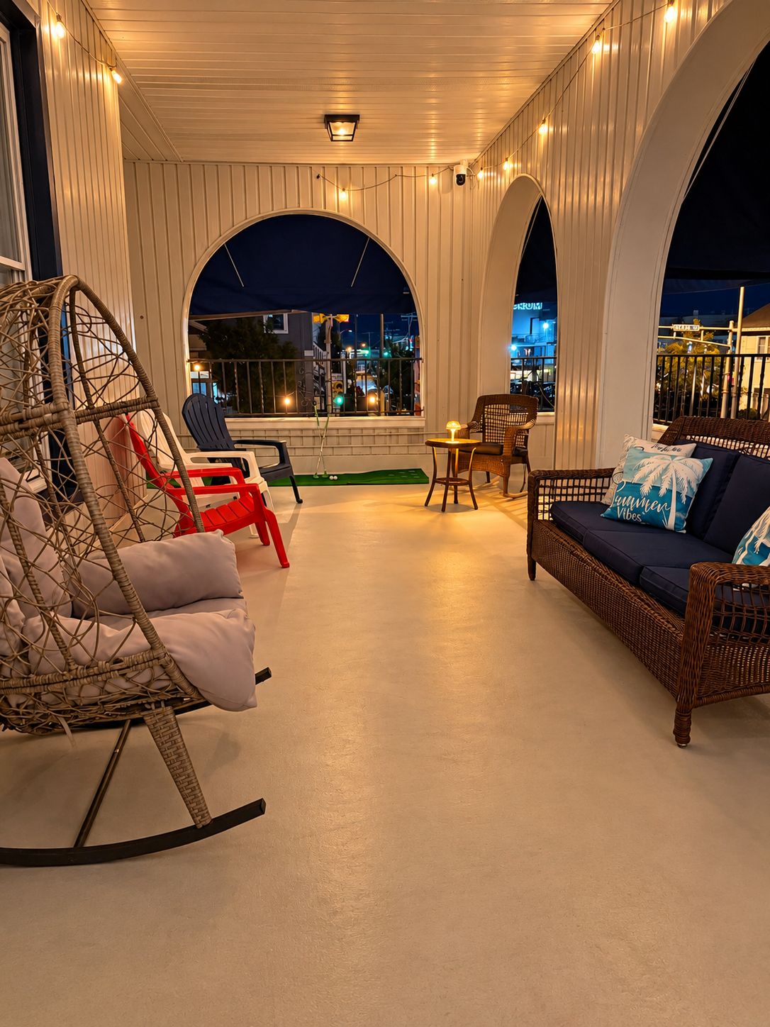 A covered outdoor seating area with wicker furniture, a table, and chairs.