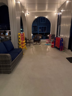 Un espacio al aire libre techado con un área de estar, un parque infantil y vista a un edificio al fondo.