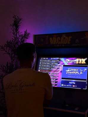 Una persona de pie frente a una consola de videojuegos que muestra Street Fighter II Champion Edition.