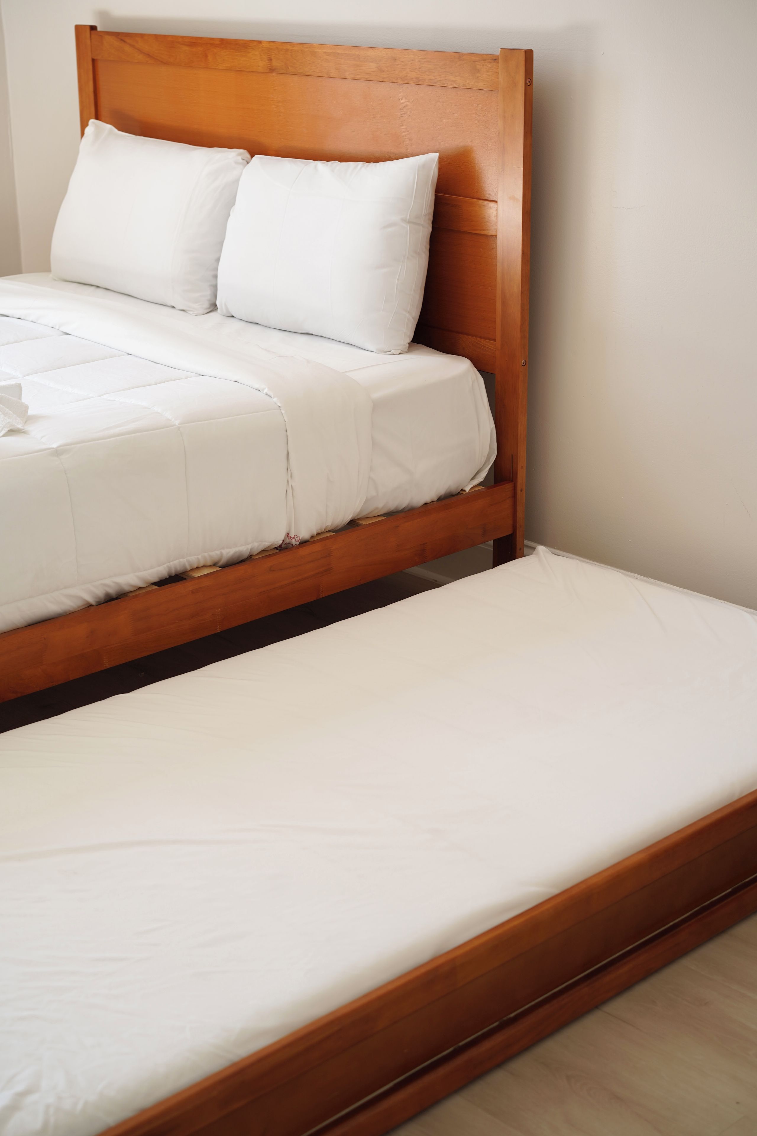 Een tweepersoonsbed met een houten hoofdbord en witte beddengoed.