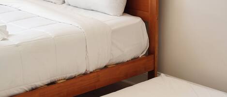 Een tweepersoonsbed met een houten hoofdbord en witte beddengoed.