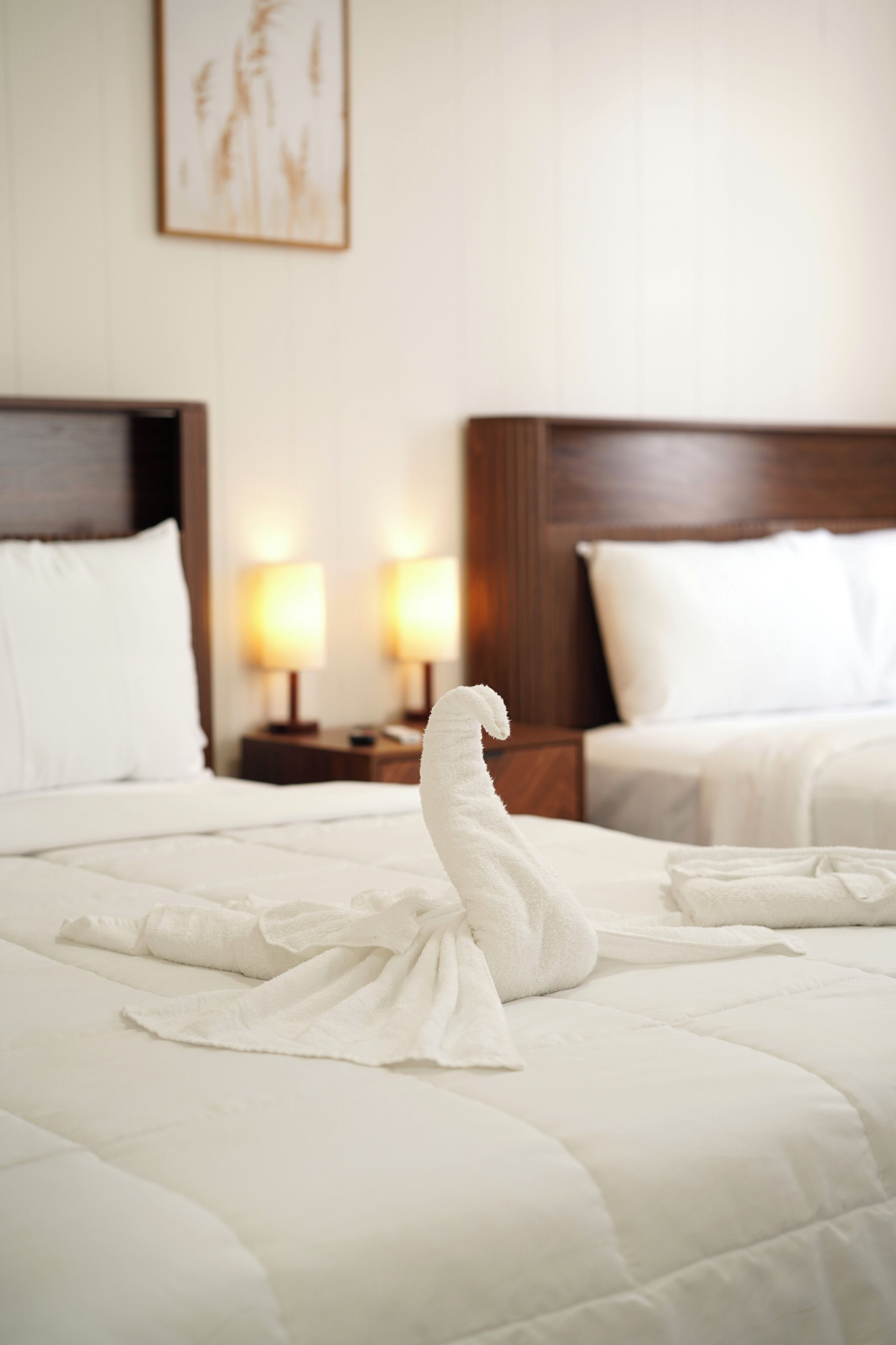 Een hotelkamer met twee bedden, elk voorzien van witte lakens en kussens, en twee bedlampjes.