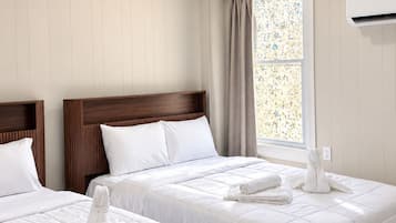 Ein Hotelzimmer mit zwei Betten, einem Fenster mit Aussicht und einer Klimaanlage.