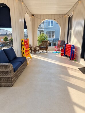 Un espacio al aire libre techado con sofá, sillas y juegos infantiles.
