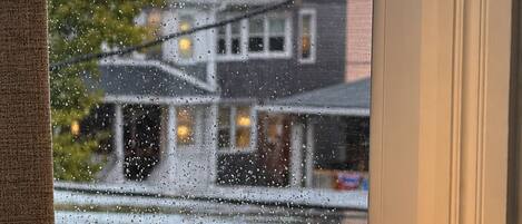 Una lámpara sobre una mesa cerca de una ventana con gotas de lluvia en el vidrio.