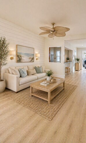 A spacious living room with a large sofa, a wooden coffee table, and a ceiling fan. - The Linda Grande Hotel (Ocean City)