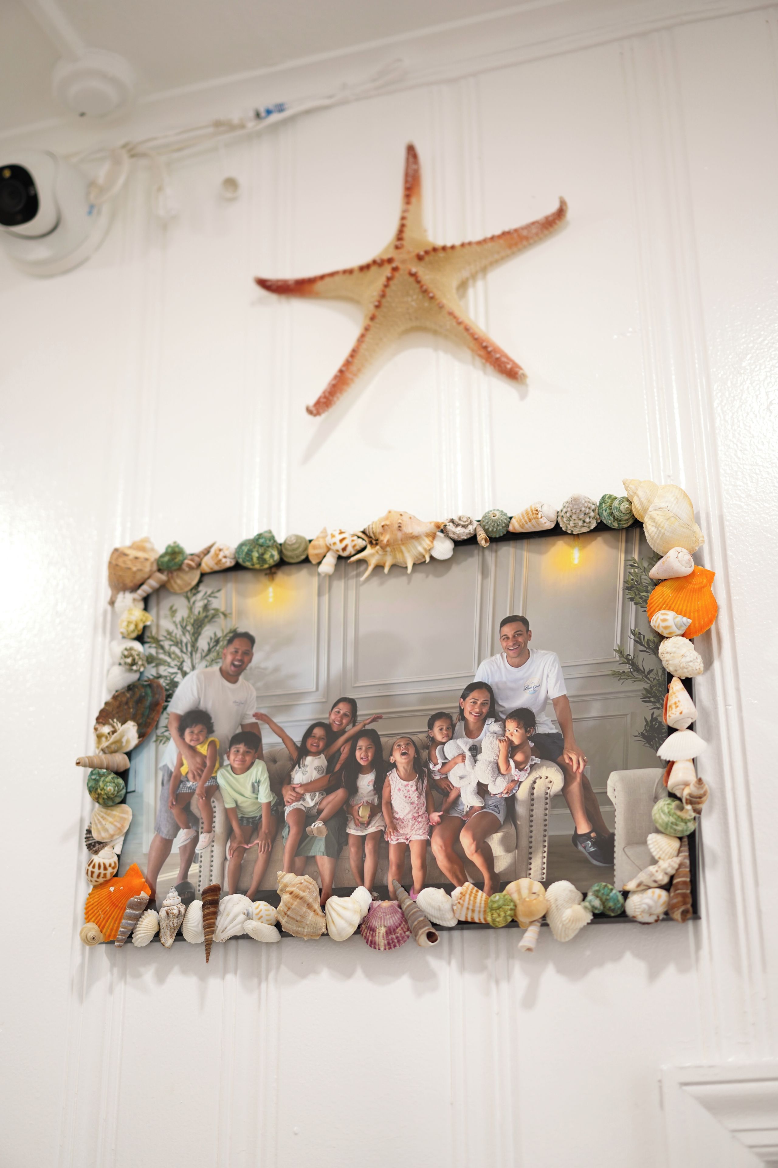 Een wanddecoratie met een fotolijst en een zeester erboven.